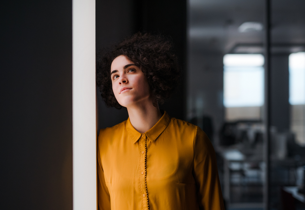 Vrouw in gele blouse kijkt naar boven